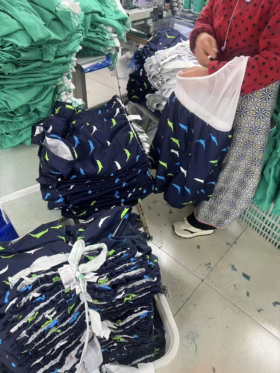 Dolphin print swim shorts with white mesh lining being finished in a garment factory